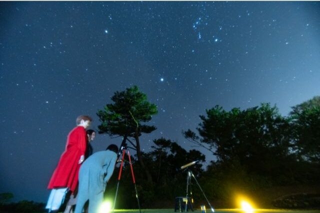 恩納村の星空観測イベントで望遠鏡を覗き込む参加者たち