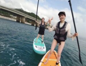 沖縄の青い海でスタンドアップパドルを楽しむ女性