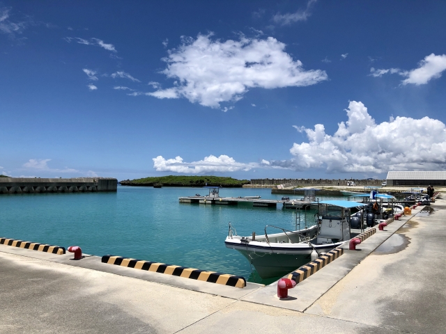 恩納村で釣りの拠点となる港。穏やかな海面に反射する青空と釣り船