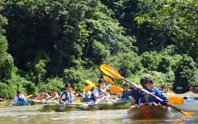 沖縄の比謝川でカヤックを体験する修学旅行生