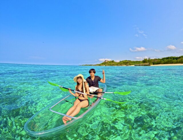 沖縄の透明度抜群な海でクリアサップを楽しむカップル。