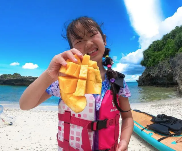 沖縄の海辺でマンゴーを楽しむ子ども