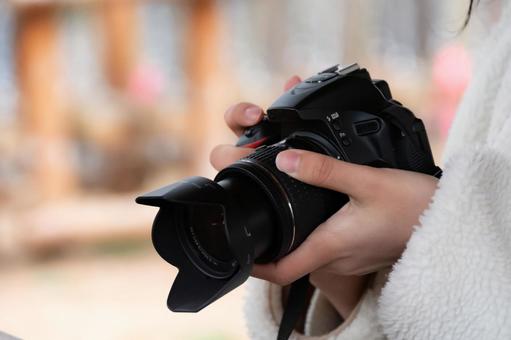 一眼レフカメラを構えて星空撮影の準備をする、白い服を着た女性の手元