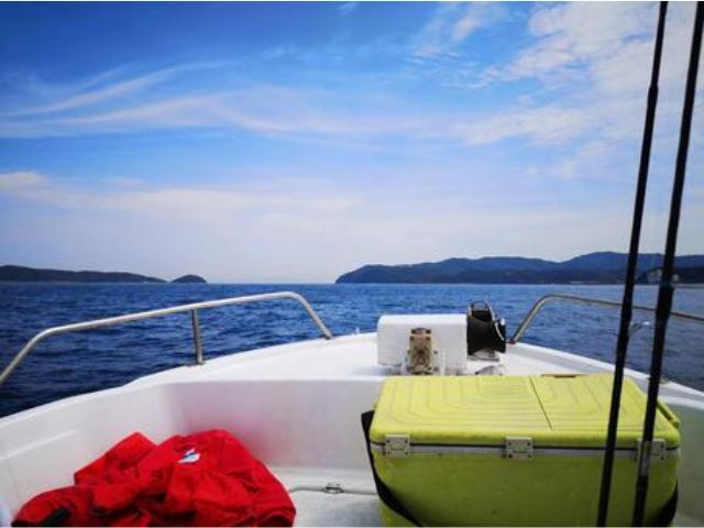 恩納村の釣り船からの景色。白い船体と青い海、遠くに見える山並み