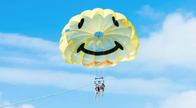 沖縄の空に浮かぶスマイル模様が可愛い人気のパラセーリング。