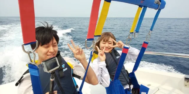 沖縄でパラセーリング体験中のカップル。フライト直前の笑顔。