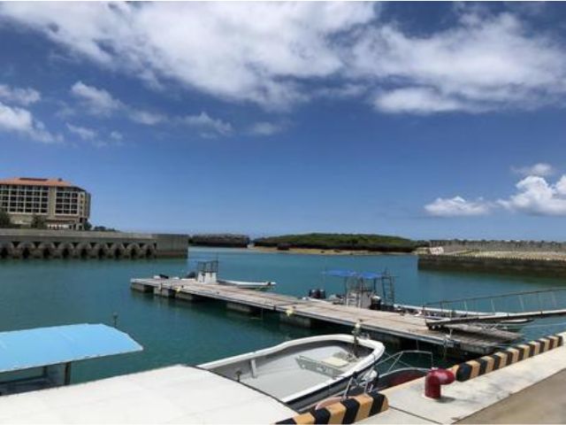 恩納村の釣り船乗り場。エメラルドグリーンの海に浮かぶ桟橋と小船