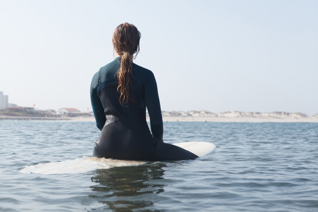 沖縄の海でサーフィンを楽しむ女性の姿