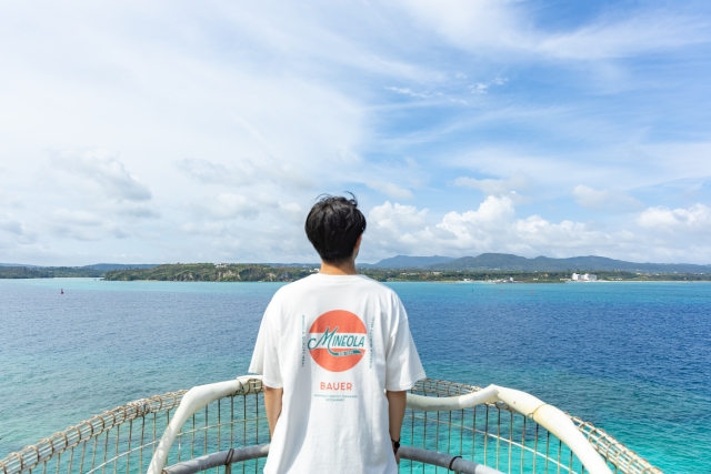沖縄ツアーで絶景の海を眺める男性の後ろ姿