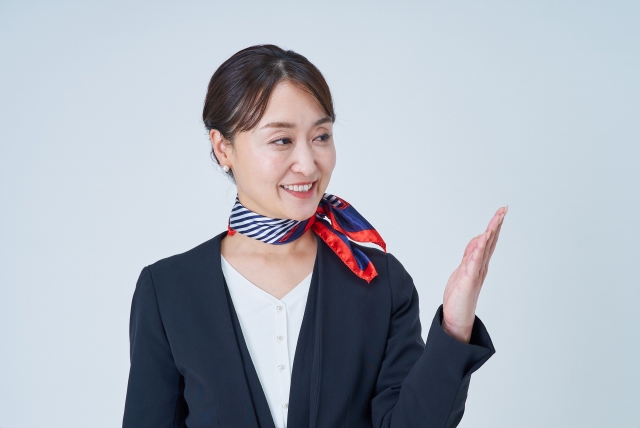 案内のポーズをするスカーフを巻いた女性