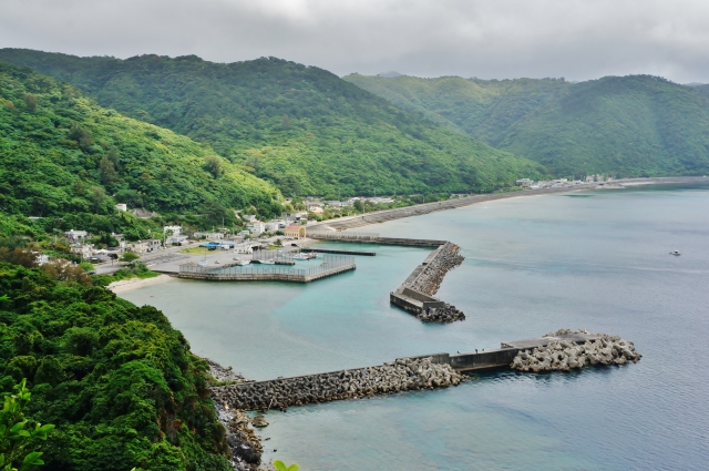 緑豊かな山々に囲まれた沖縄の漁港を俯瞰。テトラポットと複雑な地形で魚影が濃そうなポイント全景。