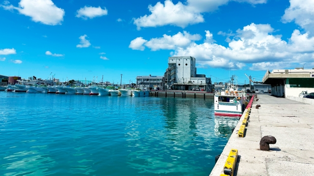 青い空とエメラルドグリーンの海が美しい沖縄の漁港と係留された漁船
