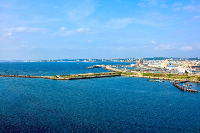 沖縄の穏やかな港の風景と、遠くに広がる街並みや水平線の眺め