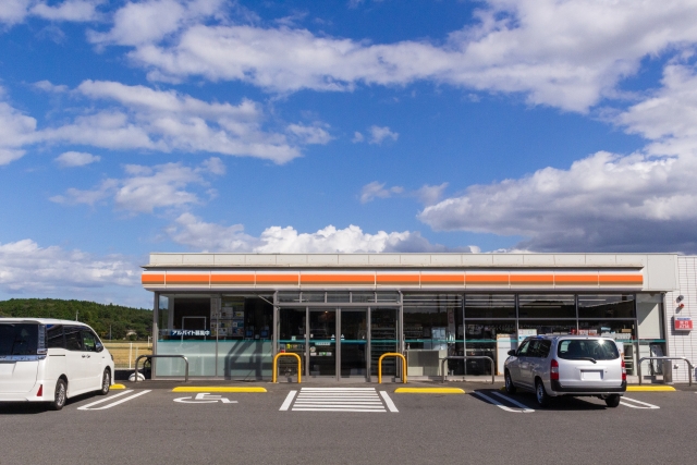 青空の下、広い駐車場を備えた沖縄のロードサイドにあるコンビニエンスストア