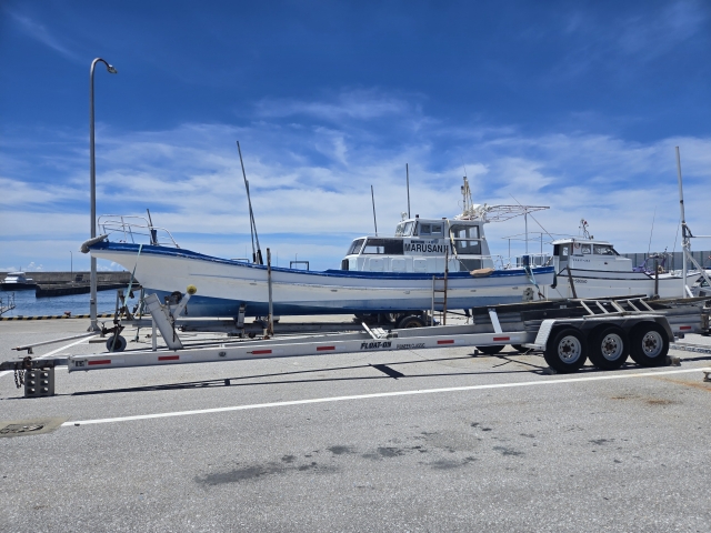 空の下、マリーナの陸上に保管されている白いボート（プレジャーボート）