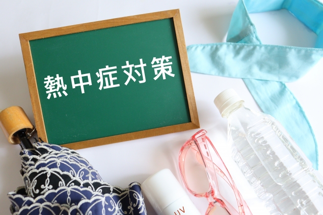 熱中症対策と書かれた黒板と、ペットボトルの水やサングラスなどの対策グッズ