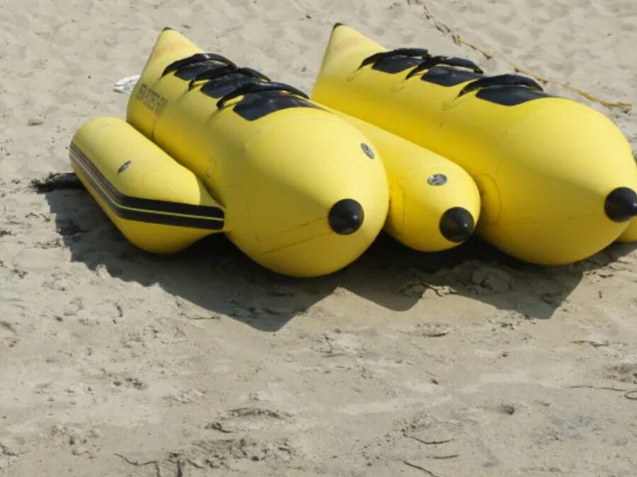 ビーチの砂浜に並べられた黄色い2艇のバナナボート。出航を待つ沖縄のマリンアクティビティ機材。