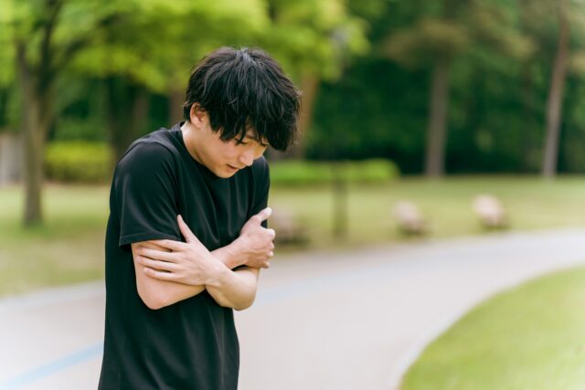 寒がる男性 黒いTシャツ